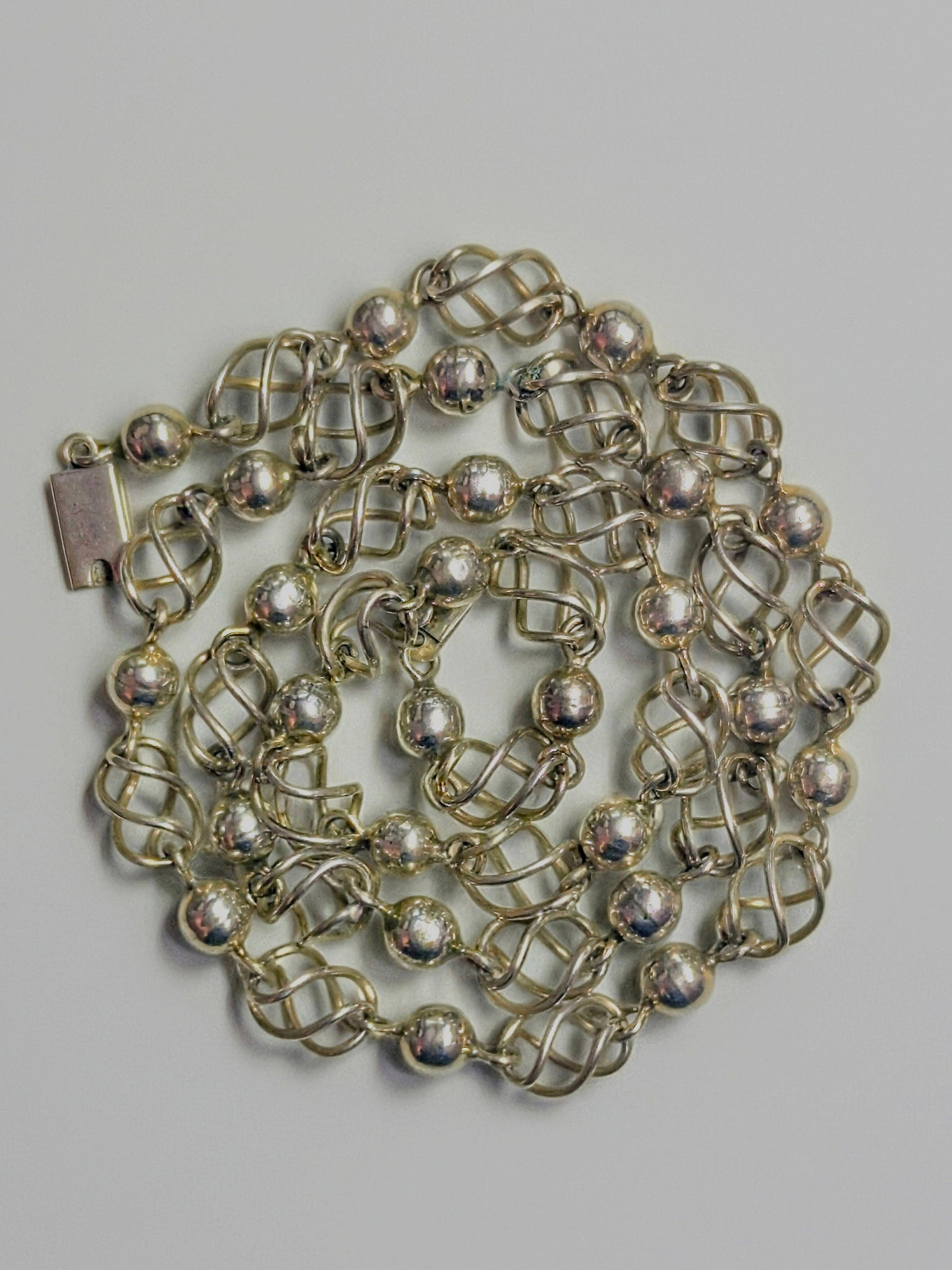 Sterling silver necklace composed of polished round beads alternating with open spiral-cage links.