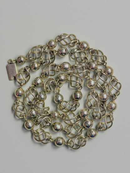 Sterling silver necklace composed of polished round beads alternating with open spiral-cage links.