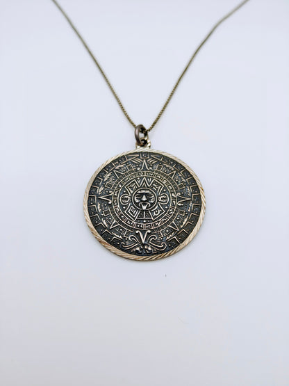 Round sterling silver pendant carved with a detailed Mesoamerican Sun Stone calendar design, oxidized for contrast.
