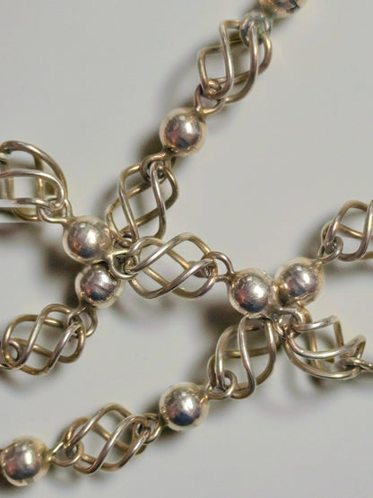Sterling silver necklace composed of polished round beads alternating with open spiral-cage links.