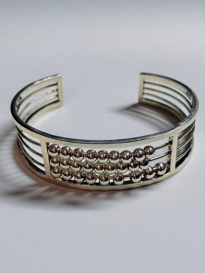 Sterling silver Abacus of Thresholds cuff bracelet with rows of movable silver beads on parallel bars.