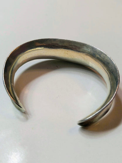 Wide vintage Mexican sterling silver bone-style cuff bracelet with curved shape on a white background.