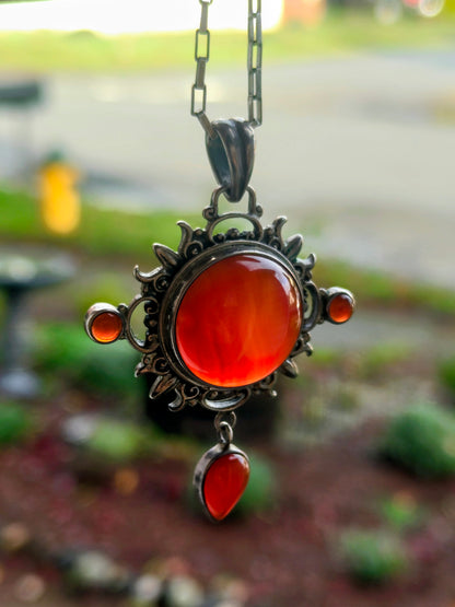 Carnelian Keeper Necklace hanging from a silver chain, glowing orange-red carnelian stones.