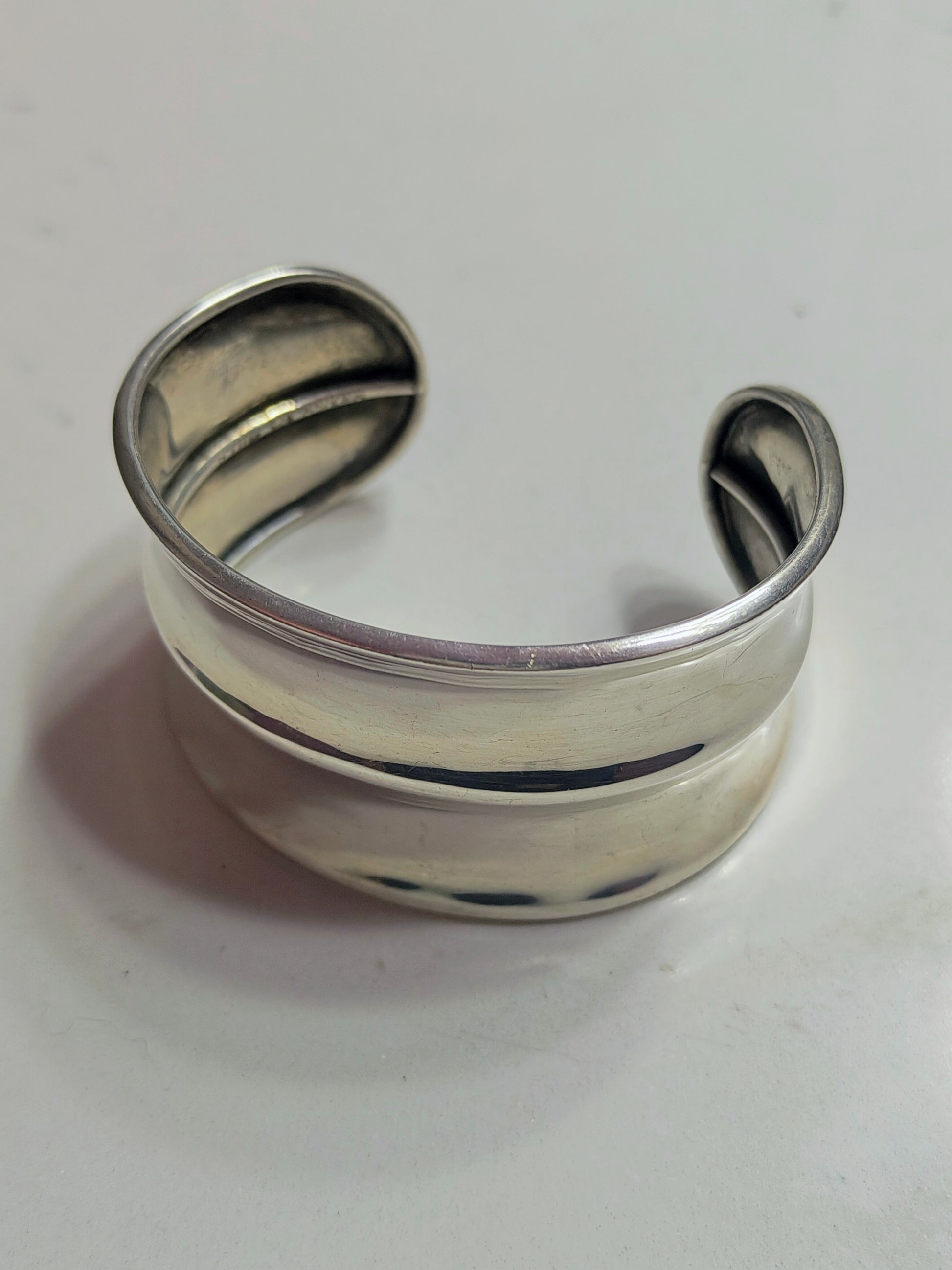 Front view of solid sterling silver horizon-band cuff bracelet with minimal profile, open-ended and slightly oval-shaped.