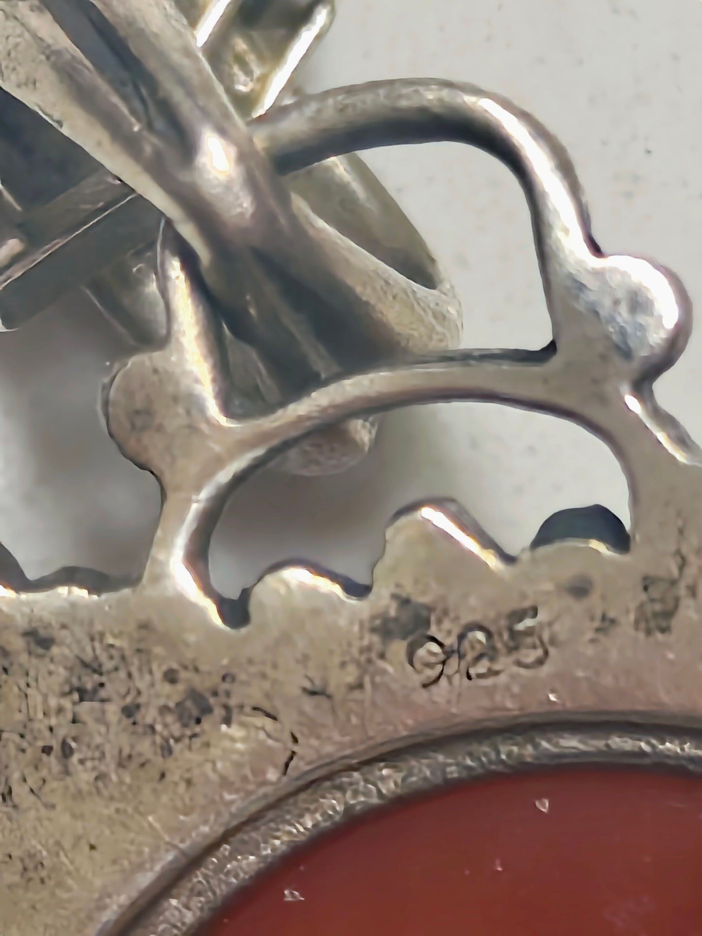 Close-up of the back of sterling silver pendant showing the “925” hallmark and textured metal around the carnelian setting